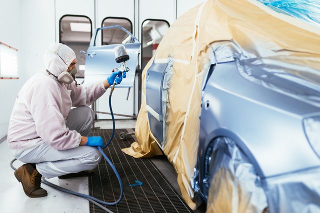 Painter refinishing a vehicle in the paint booth