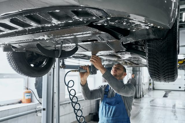Mechanic working under a vehicle on a lift